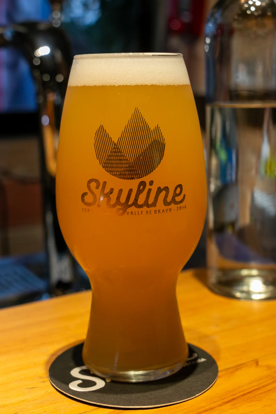 Fantasma — Hazy IPA de la marca hermana Fantasma, lata blanca y pint sobre barra de madera