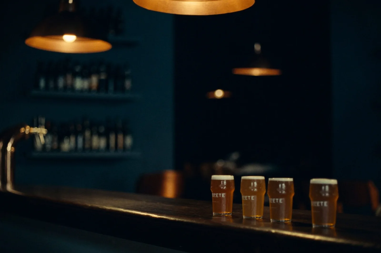 Interior de la Taberna Skyline con grifo de cobre, luz ámbar y barra de madera artesanal